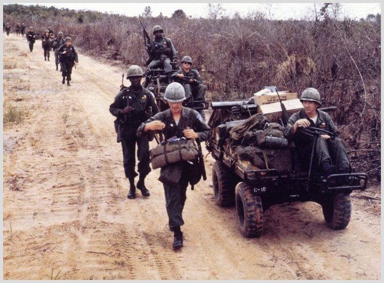 A group of soldiers walking down the road.