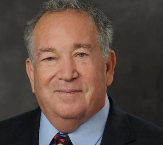 A man in a suit and tie smiling for the camera.