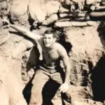 A man climbing up the side of a rock wall.