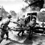 A group of soldiers carry an injured person on a stretcher.